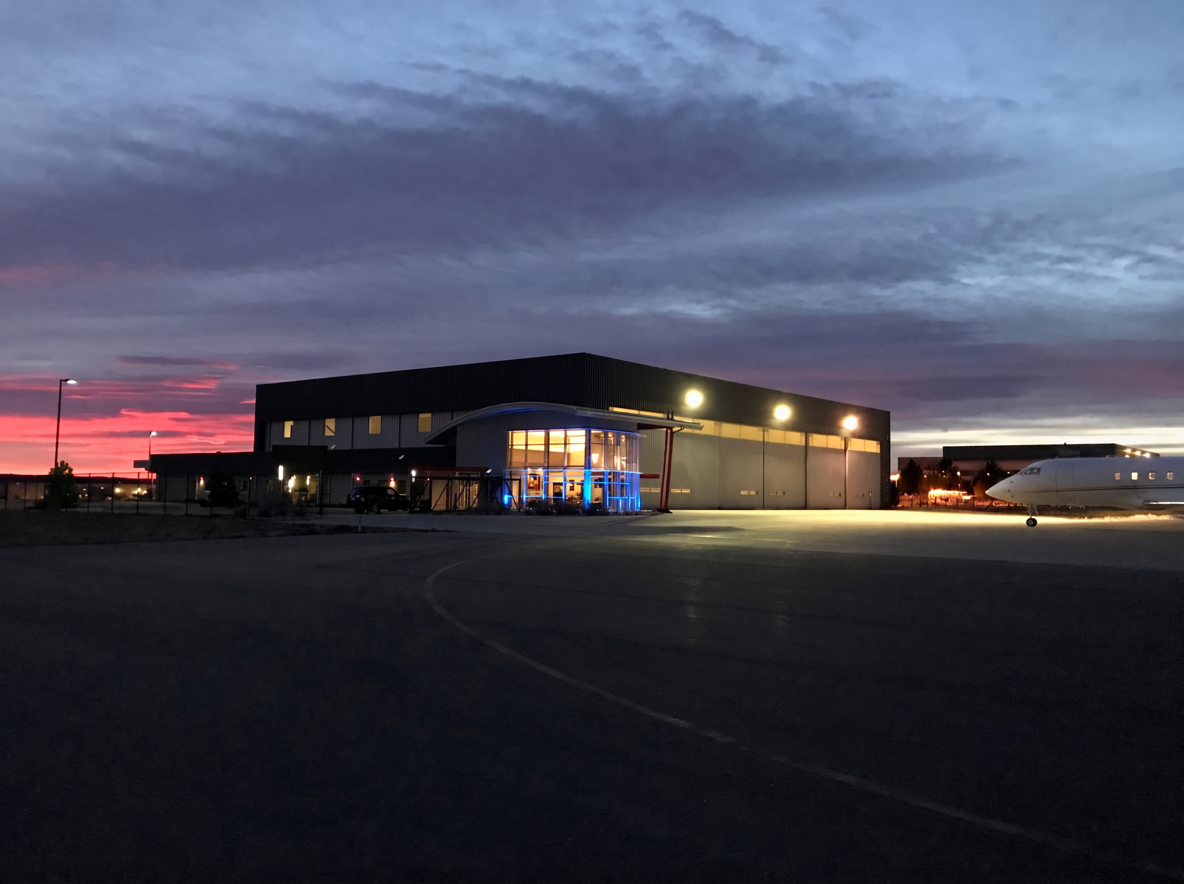 Airmax hangar at Centennial Airport at dusk with a business jet on the ramp