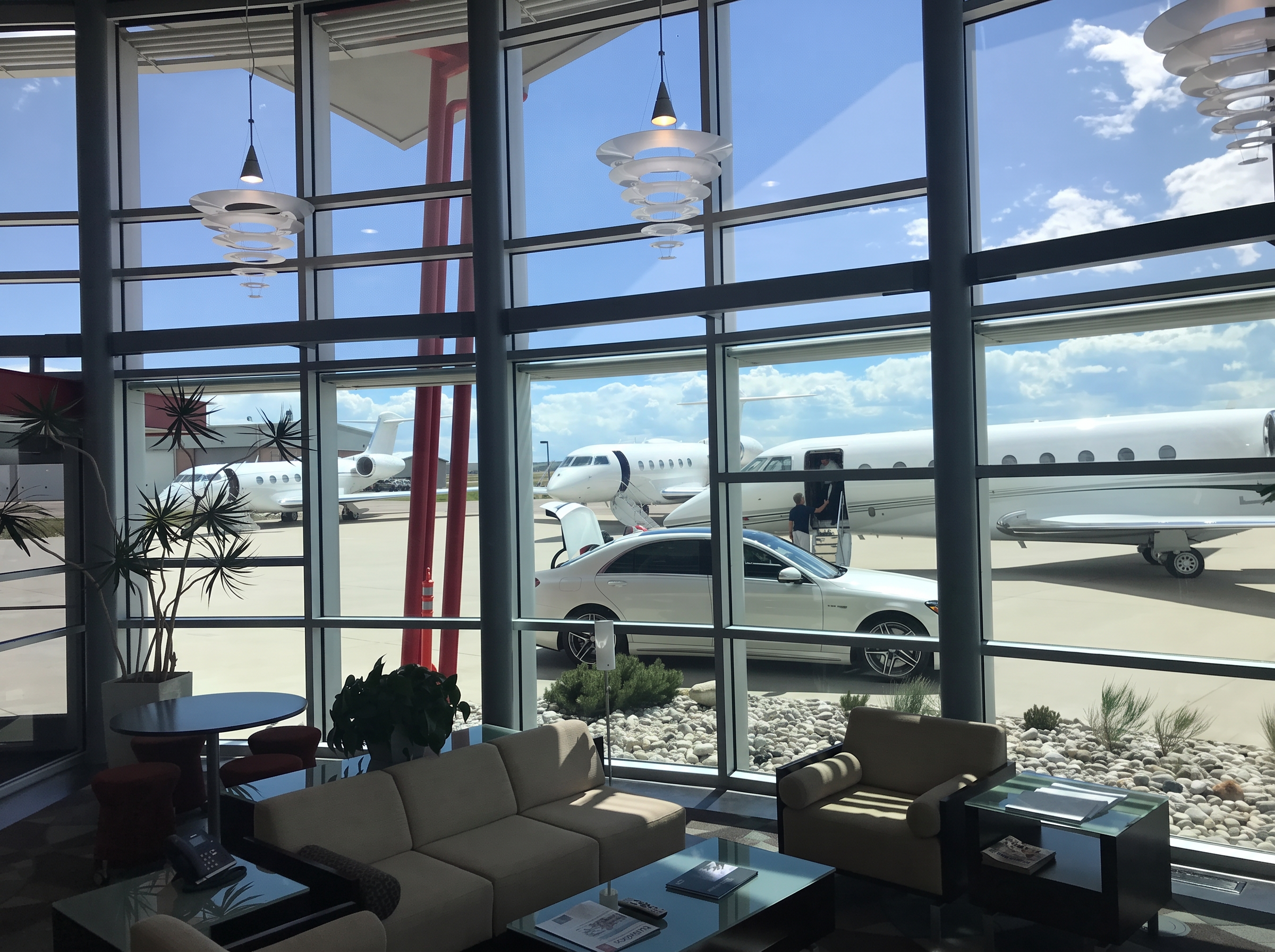 Client lounge overlooking the ramp with business jets and a car at planeside